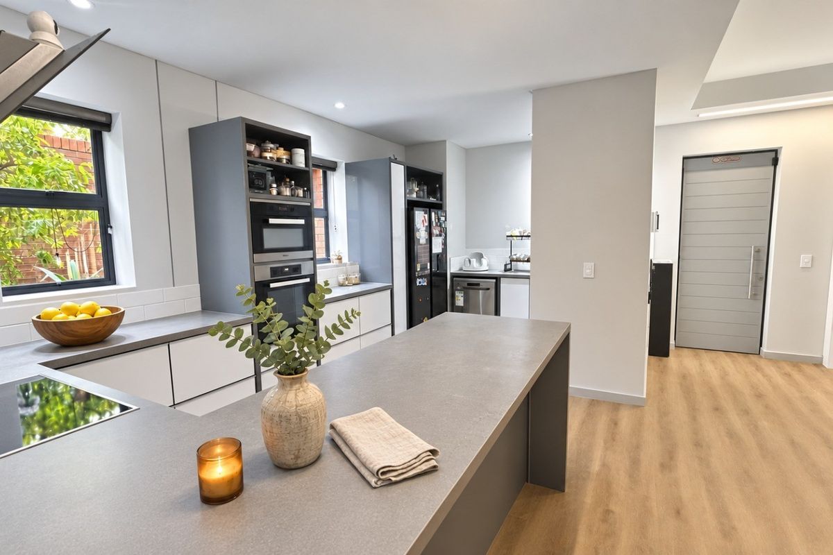 A modern, well-appointed kitchen featuring sleek cabinetry, stone countertops, a central island, and integrated appliances, finished with high-quality laminate flooring.