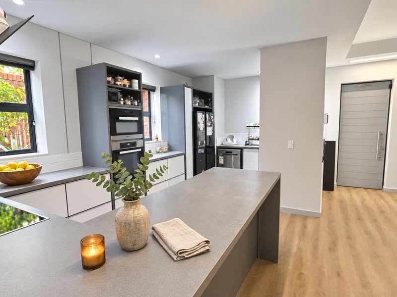 A modern, well-appointed kitchen featuring sleek cabinetry, stone countertops, a central island, and integrated appliances, finished with high-quality laminate flooring.