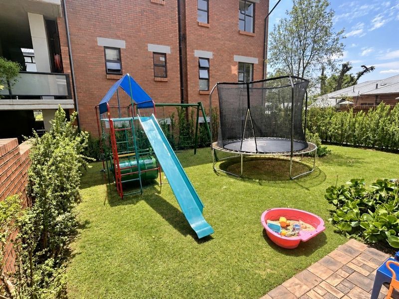 A private garden area featuring a well-maintained lawn, brick boundary wall, and a paved patio section, suitable for outdoor recreation.