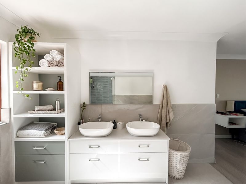 Modern bathroom featuring a double vanity with vessel sinks, integrated storage shelving, and contemporary tiled finishes.
