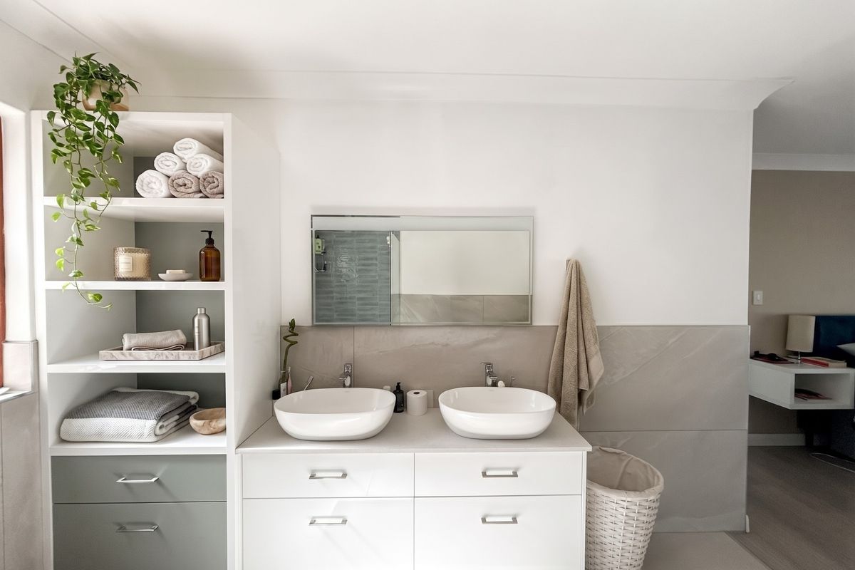 Modern bathroom featuring a double vanity with vessel sinks, integrated storage shelving, and contemporary tiled finishes.