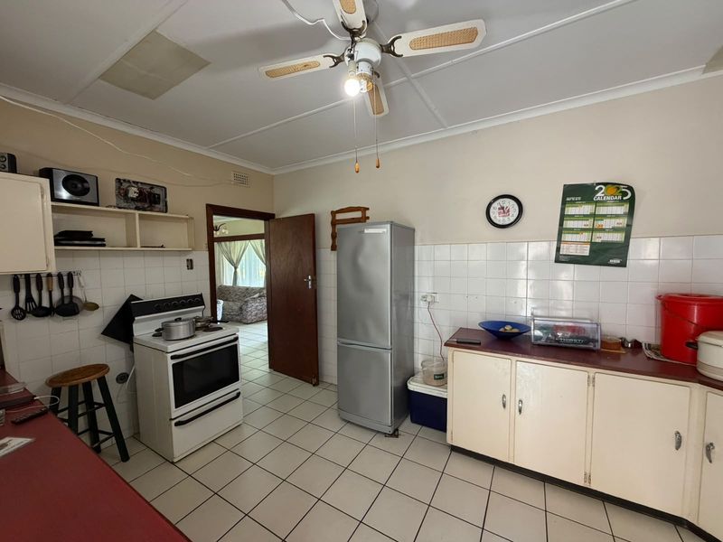 A functional kitchen featuring tiled flooring, a tiled backsplash, built-in cabinetry, and a freestanding stove, with a ceiling fan and coved ceiling details.