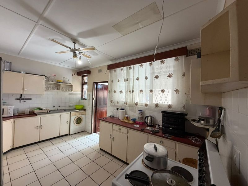 A dated kitchen featuring tiled flooring, built-in cabinetry, and a tiled backsplash, requiring cosmetic updates to modernize the space.