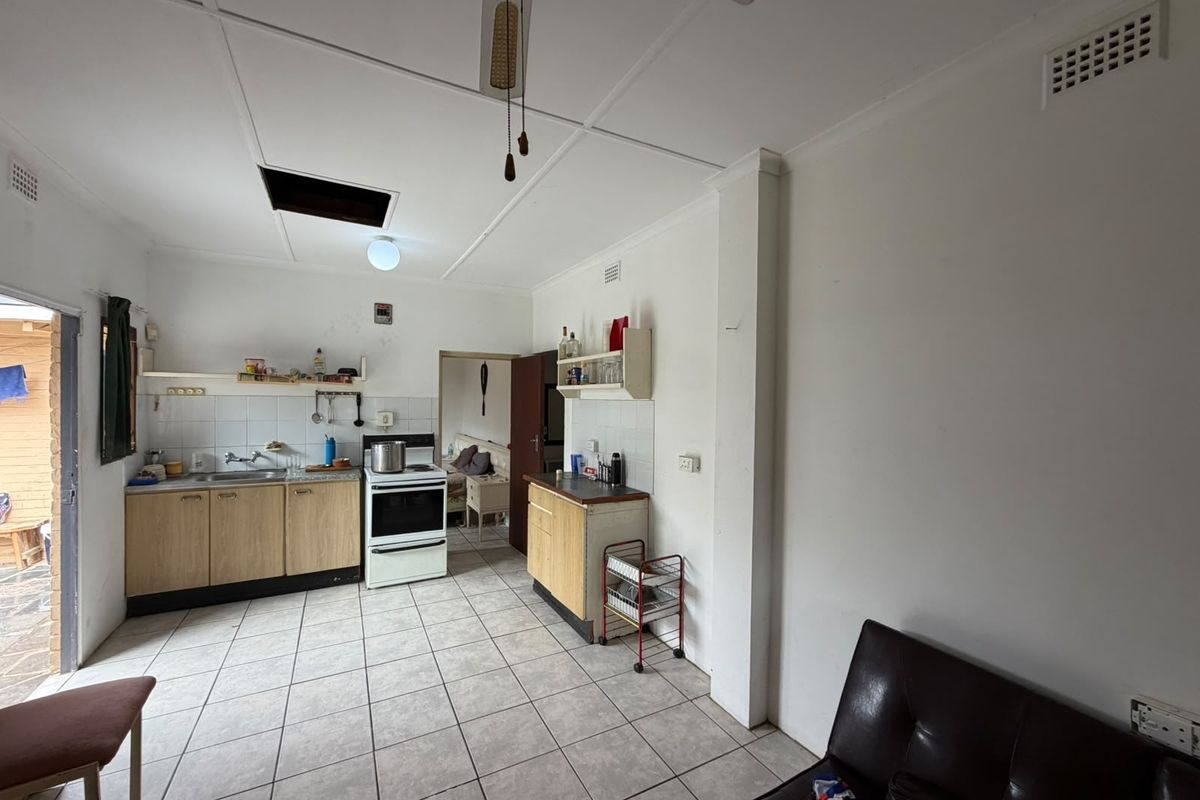 A functional kitchen area featuring tiled flooring, built-in cabinetry, and a freestanding stove, requiring cosmetic updates to improve its overall condition and appeal.
