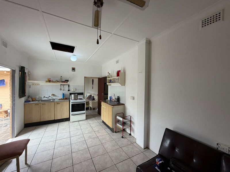 A functional kitchen area featuring tiled flooring, built-in cabinetry, and a freestanding stove, requiring cosmetic updates to improve its overall condition and appeal.