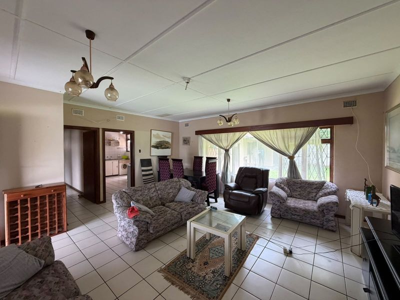 Spacious open-plan living and dining area featuring tiled flooring, large windows with security bars, and direct access to the kitchen area.