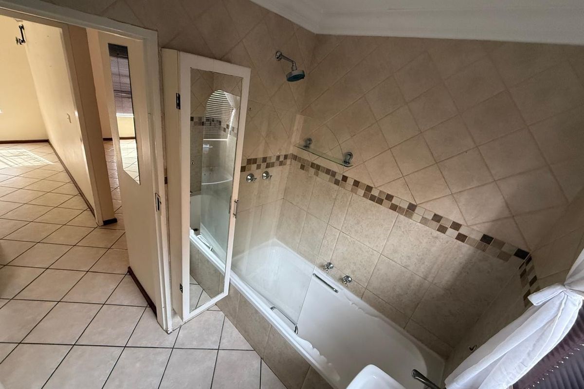 A functional bathroom featuring a built-in bathtub with shower attachment, tiled walls with decorative accents, and a vanity basin.