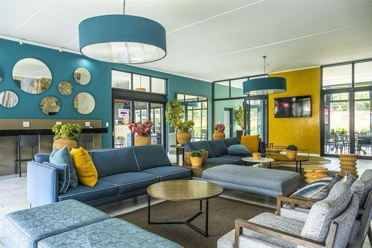 A spacious and modern living area featuring large glass sliding doors, tiled flooring, and a built-in breakfast bar, creating a bright and inviting atmosphere.