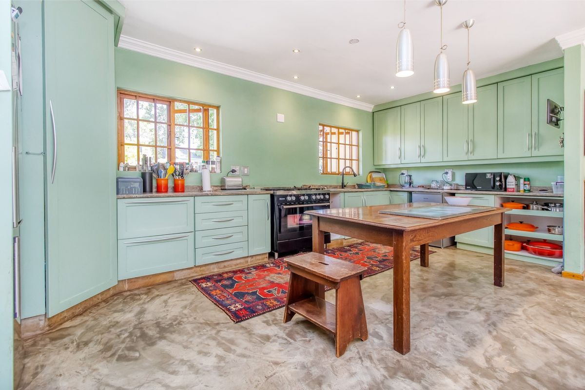 Spacious kitchen featuring mint green cabinetry, polished concrete floors, stone countertops, and a large central island, offering a functional and characterful cooking space.