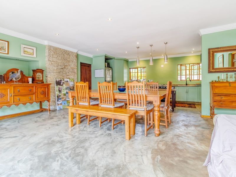 Spacious open-plan living and dining area featuring polished concrete floors, a stone-clad fireplace, and a functional kitchen with integrated cabinetry.