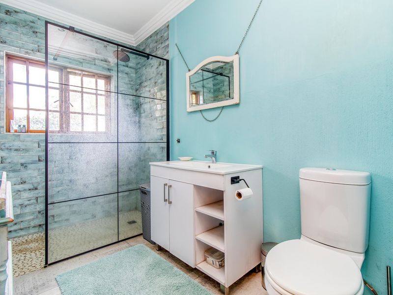 A bright bathroom featuring a walk-in shower with a glass screen, a modern vanity unit, and a standard toilet.