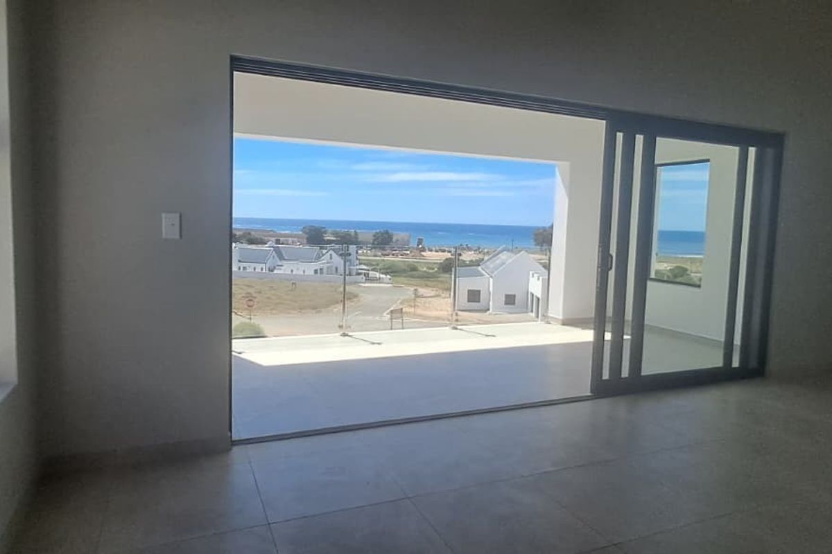 Spacious living area featuring large sliding glass doors that open onto a covered patio with scenic coastal views.