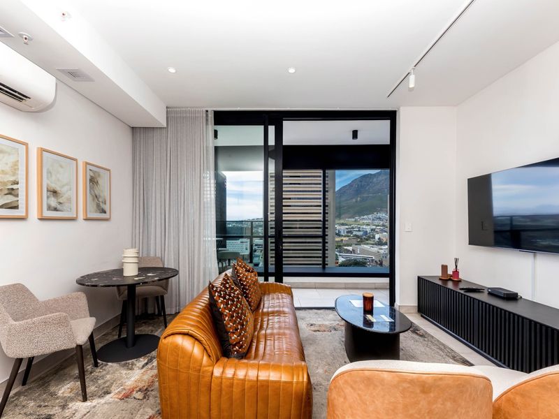 Modern living room featuring recessed lighting, split-system air conditioning, and large sliding glass doors opening to a balcony with mountain views.