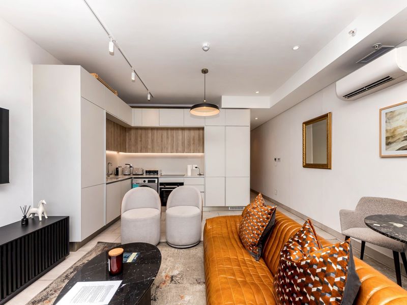 Modern open-plan living area featuring a sleek, integrated kitchen with contemporary cabinetry, high-quality finishes, and efficient split-system air conditioning.
