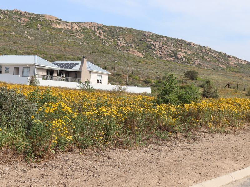 A view of a residential property featuring a house with solar panels, set against a scenic rocky hillside with natural vegetation.