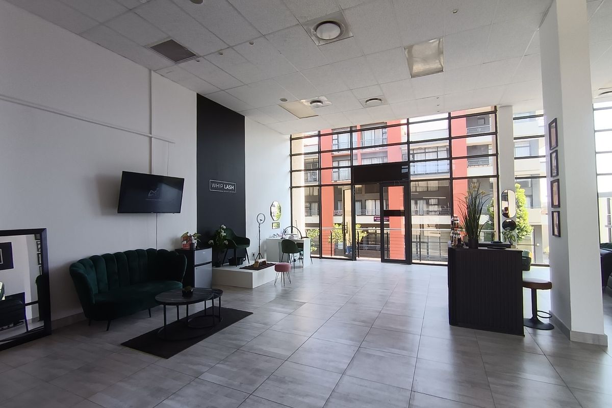 Spacious open-plan retail unit featuring high ceilings, large glass windows providing ample natural light, and modern tiled flooring throughout.