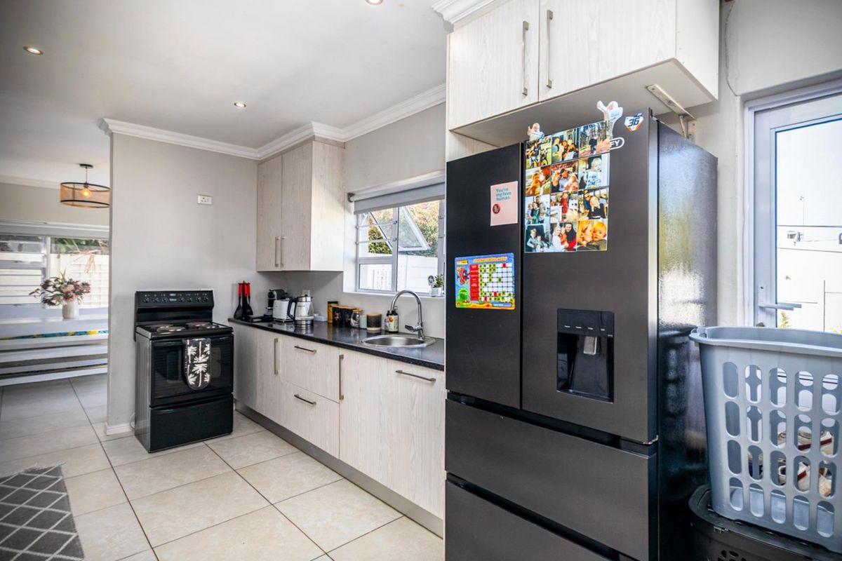 A functional kitchen featuring light-toned cabinetry, dark countertops, tiled flooring, and recessed lighting, offering a clean and practical workspace.