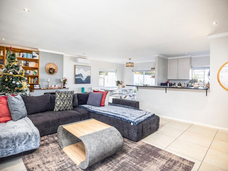 Spacious open-plan living area featuring tiled floors, recessed lighting, built-in shelving, and a functional kitchen with a breakfast bar.