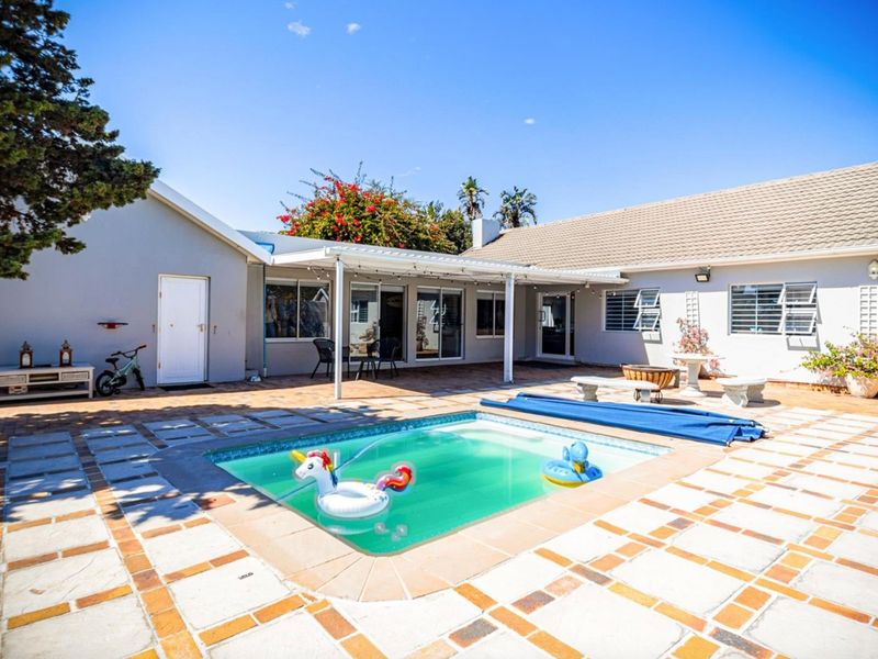 Outdoor pool area featuring a tiled deck, covered patio space, and direct access to the home through sliding glass doors.