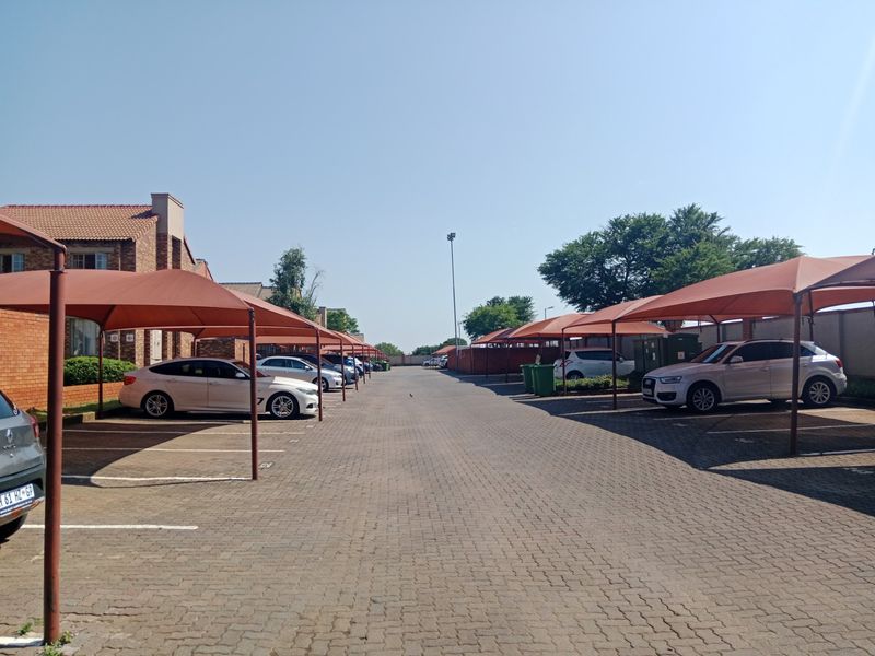 Exterior view of the apartment complex parking area featuring paved driveways and covered shade cloth parking bays.