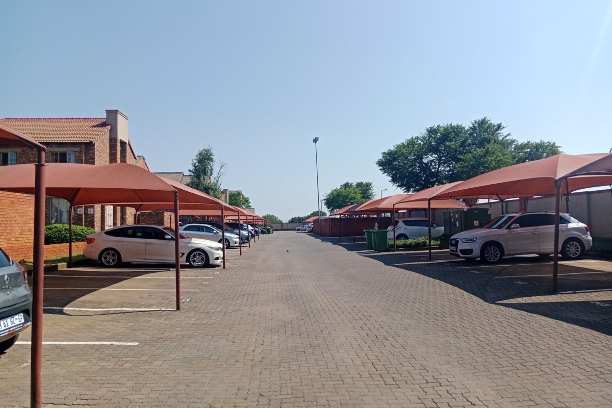 Exterior view of the apartment complex parking area featuring paved driveways and covered shade cloth parking bays.