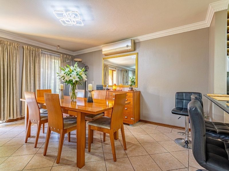 Open-plan dining area featuring tiled flooring, crown molding, a built-in wine rack, and a breakfast bar, creating a functional and connected living space.