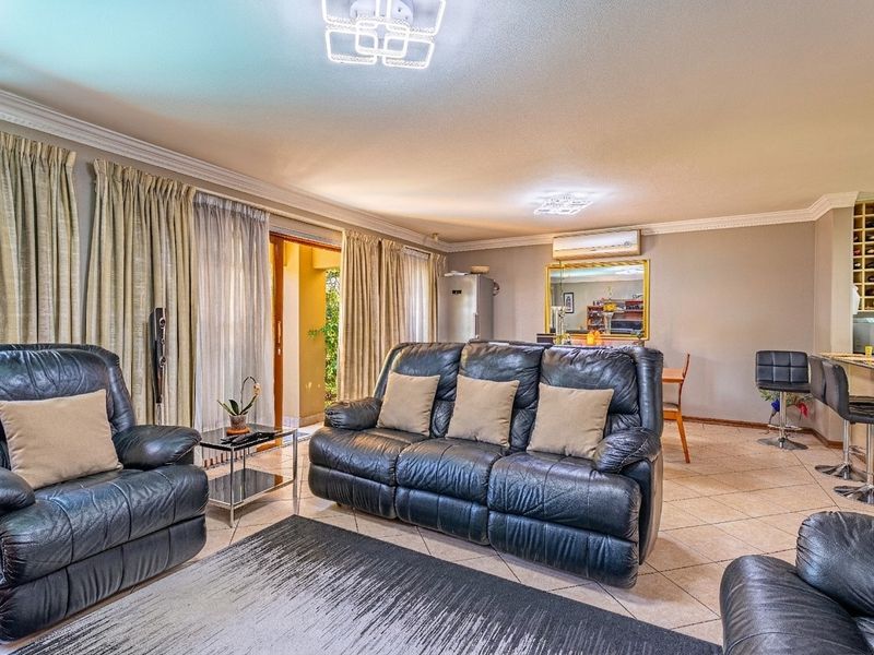Spacious open-plan living area featuring tiled floors, crown molding, a built-in bar, and direct access to an outdoor patio through sliding glass doors.