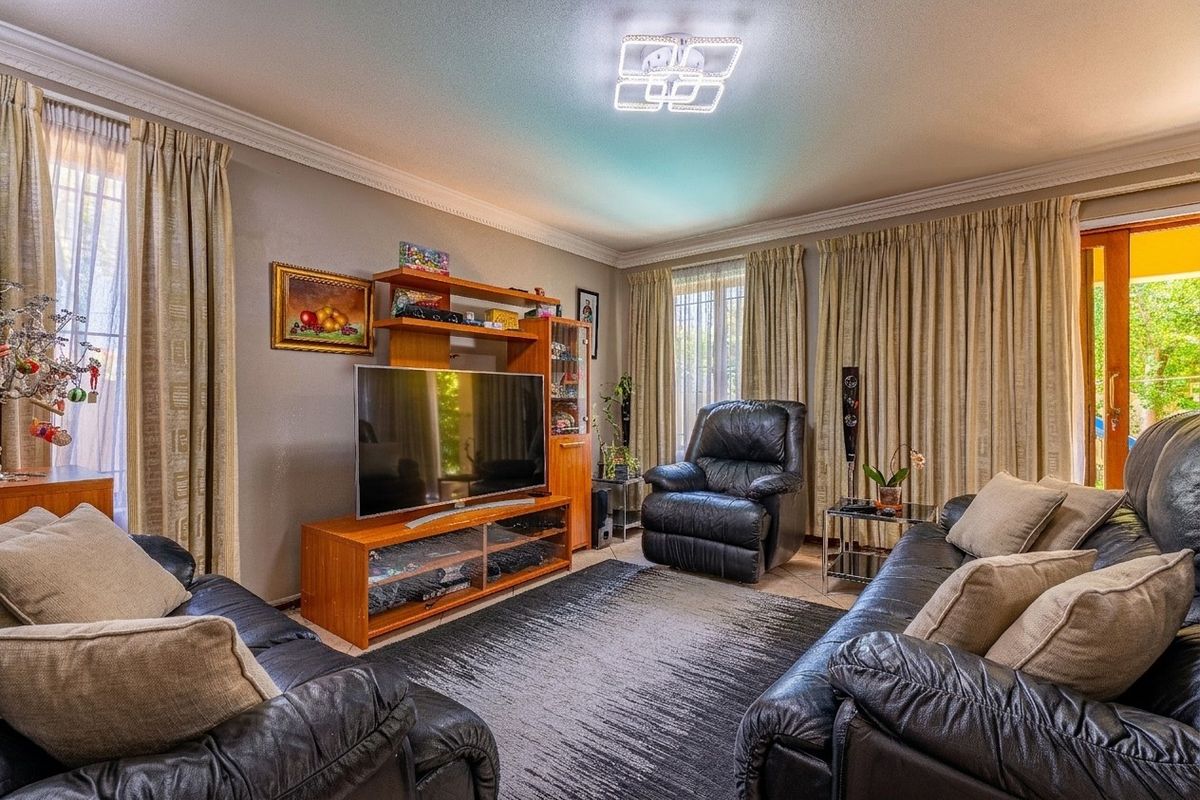 A comfortable living room featuring tiled flooring, crown molding, and a sliding glass door providing access to the outdoor area.