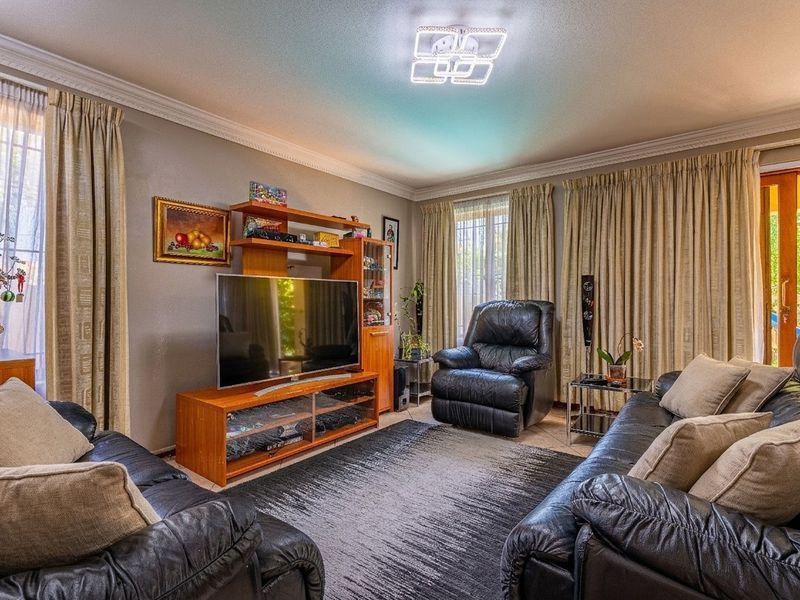 A comfortable living room featuring tiled flooring, crown molding, and a sliding glass door providing access to the outdoor area.