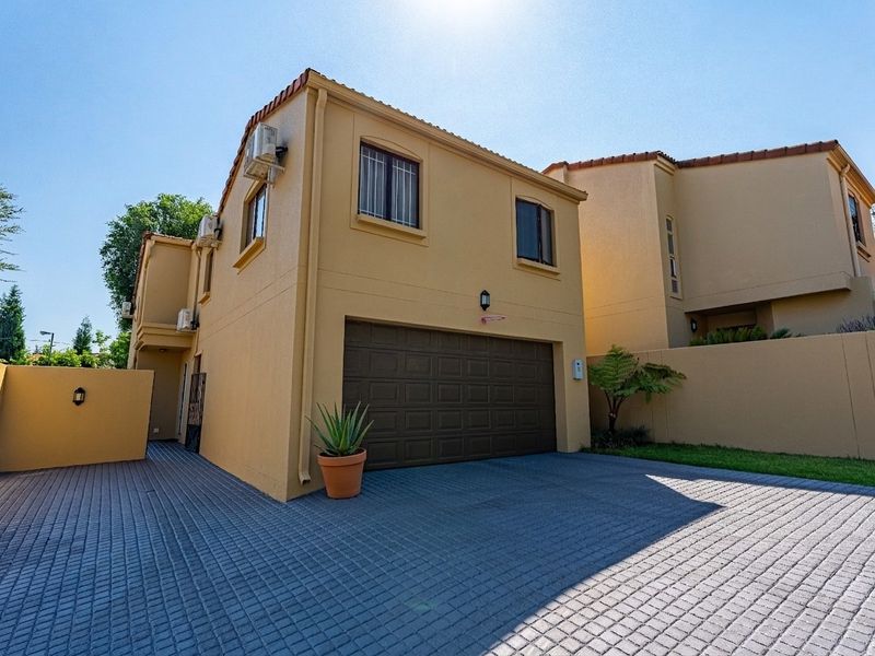 Front exterior view of a residential property featuring a paved driveway, double garage, and boundary wall with integrated exterior lighting.