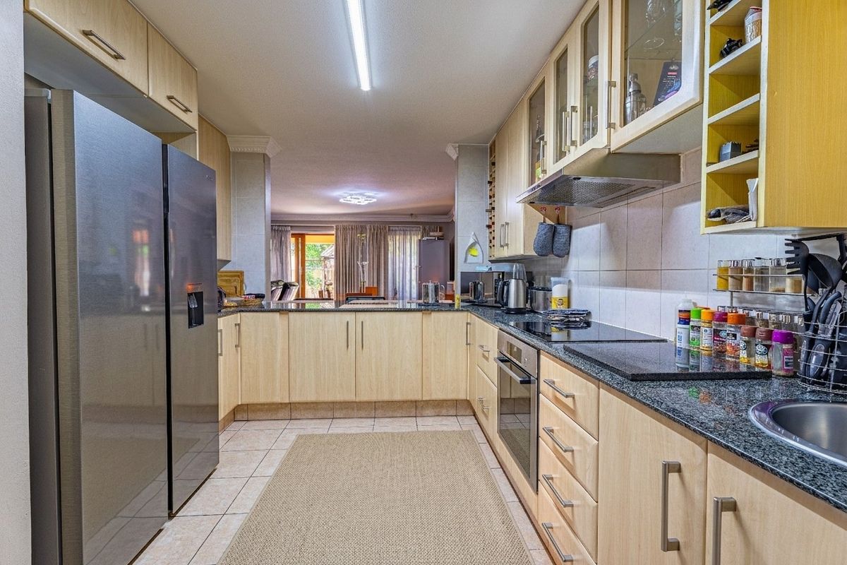 Functional kitchen featuring light wood cabinetry, granite countertops, built-in oven, and hob, with a seamless flow into the adjacent living area.