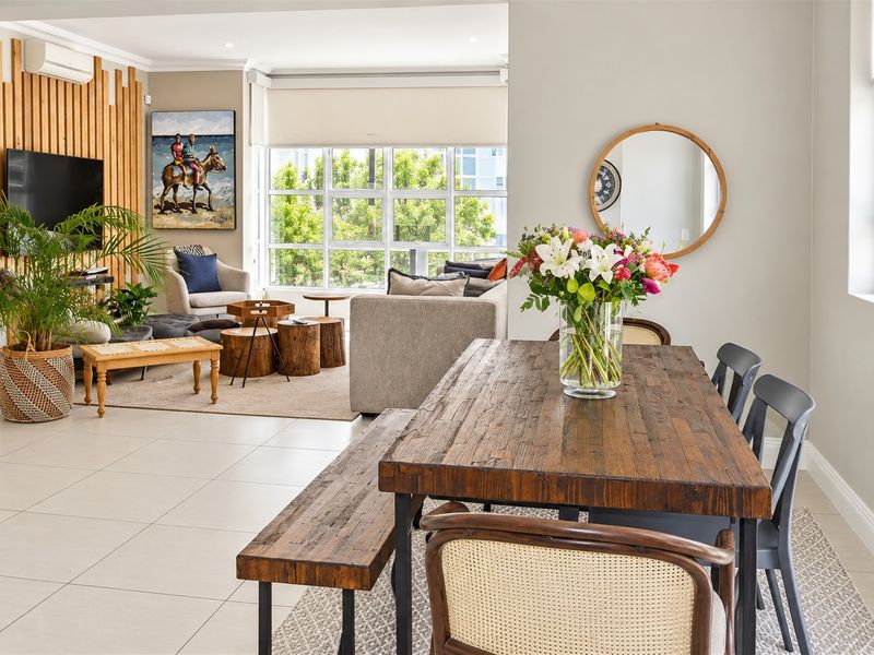 Spacious open-plan living and dining area featuring tiled flooring, timber feature wall paneling, and large windows providing ample natural light.