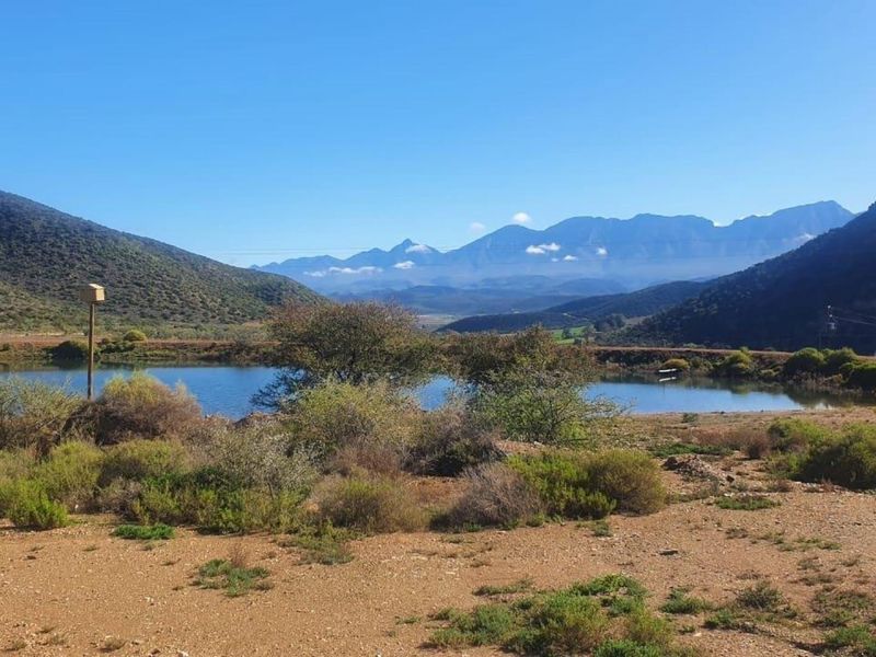 A scenic view of a farm dam set against a backdrop of rolling mountains and natural landscape.