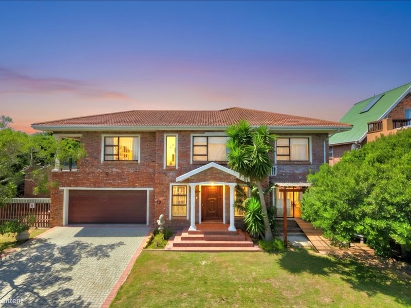 A well-maintained double-story brick residence featuring a tiled roof, double garage, paved driveway, and an inviting covered entrance with architectural columns.