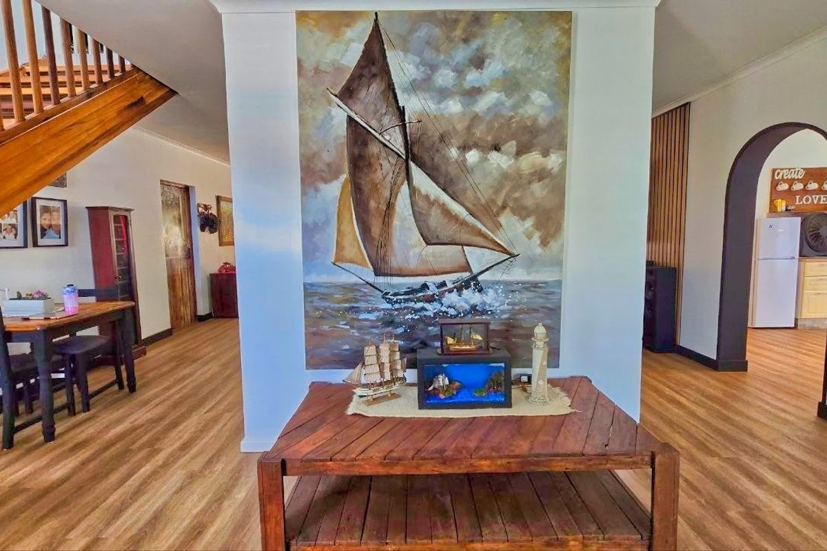 Spacious living area featuring laminate flooring, a wooden staircase with balustrade, and an arched entryway leading to adjacent rooms.