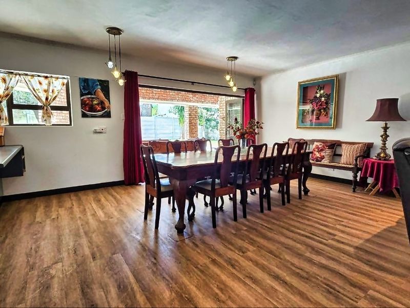 Spacious open-plan living and dining area featuring wood-look laminate flooring, modern pendant lighting, and large sliding doors providing access to the outdoor patio.