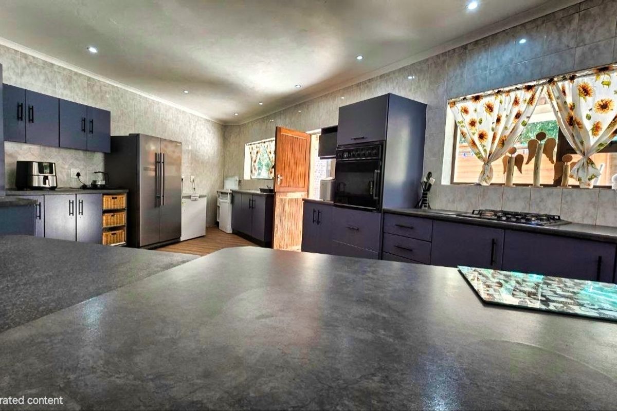 A spacious kitchen featuring dark blue cabinetry, stone-look countertops, built-in oven, gas hob, and recessed lighting, offering a functional and modern layout.