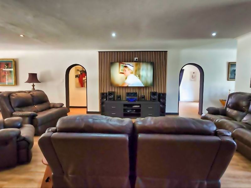 Spacious living room featuring a modern timber slat feature wall, recessed downlighting, and elegant arched doorways leading to adjacent areas.