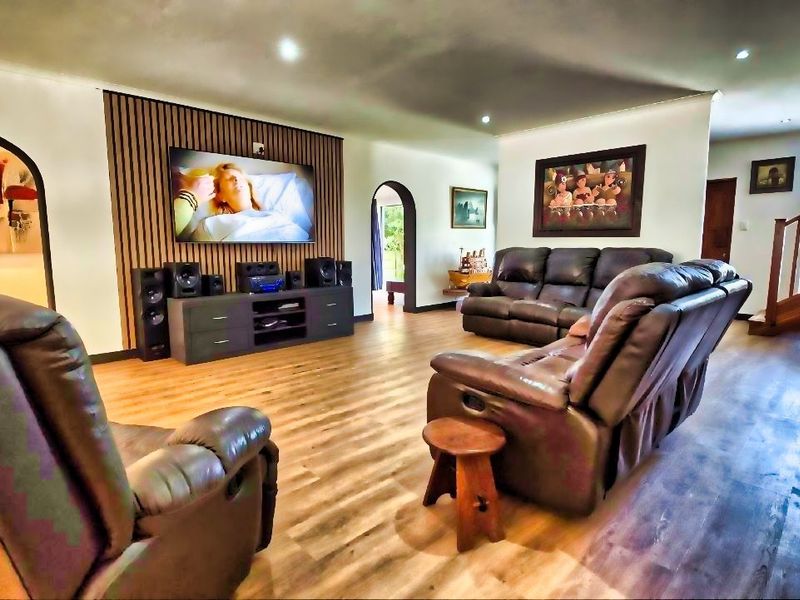 Spacious living room featuring a modern timber slat feature wall, recessed downlighting, laminate flooring, and an elegant timber staircase.