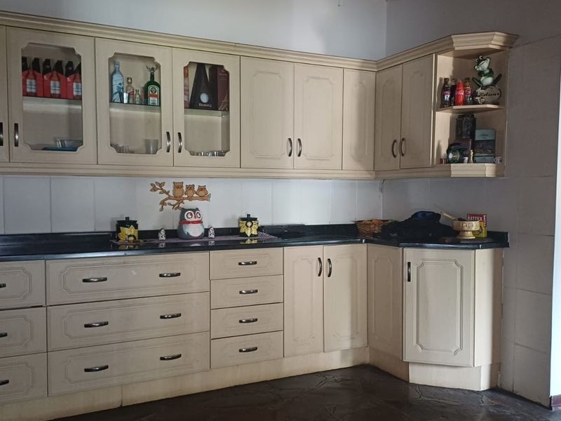 A functional kitchen featuring light-toned laminate cabinetry, black granite countertops, and a tiled backsplash, offering ample storage and workspace.