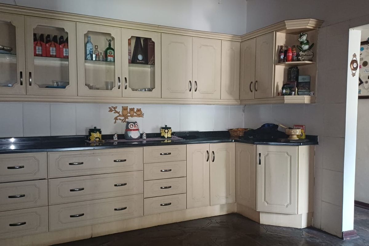 A functional kitchen featuring light-toned laminate cabinetry, black granite countertops, and a tiled backsplash, offering ample storage and workspace.