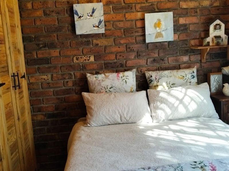 A cozy bedroom featuring a rustic exposed brick feature wall and a built-in wooden wardrobe.