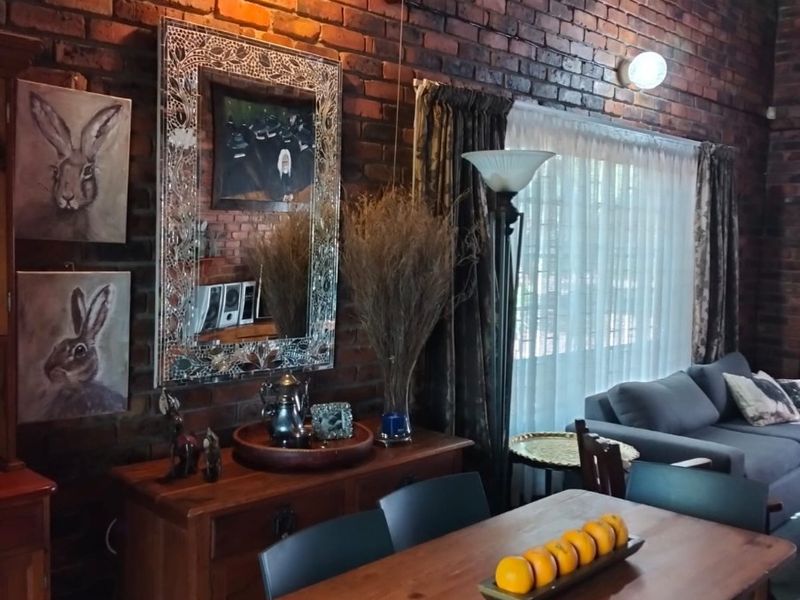 A cozy living area featuring a high vaulted ceiling with exposed thatch and a prominent rustic exposed brick wall.