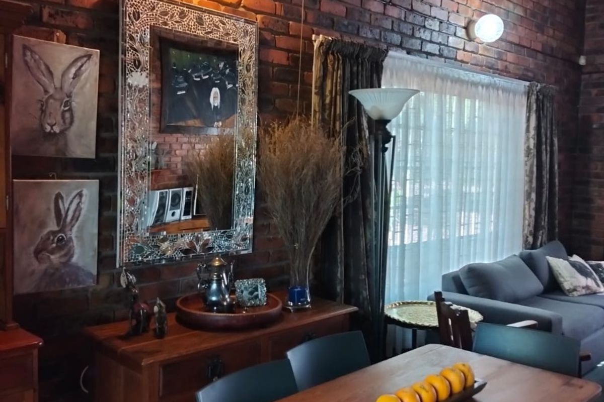 A cozy living area featuring a high vaulted ceiling with exposed thatch and a prominent rustic exposed brick wall.