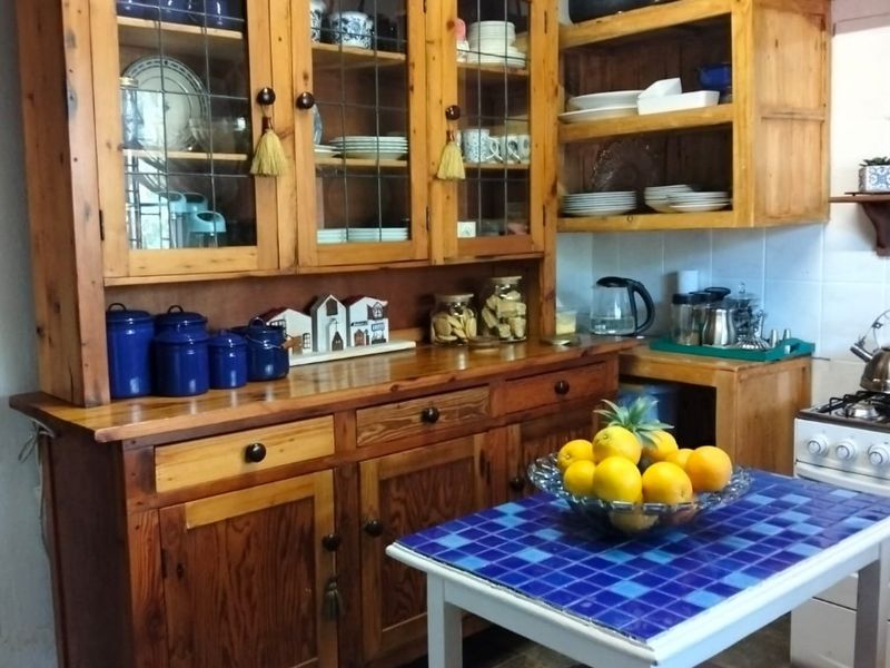 A rustic kitchen featuring traditional wooden cabinetry, exposed ceiling beams, and tiled flooring, offering a warm and characterful cooking space.
