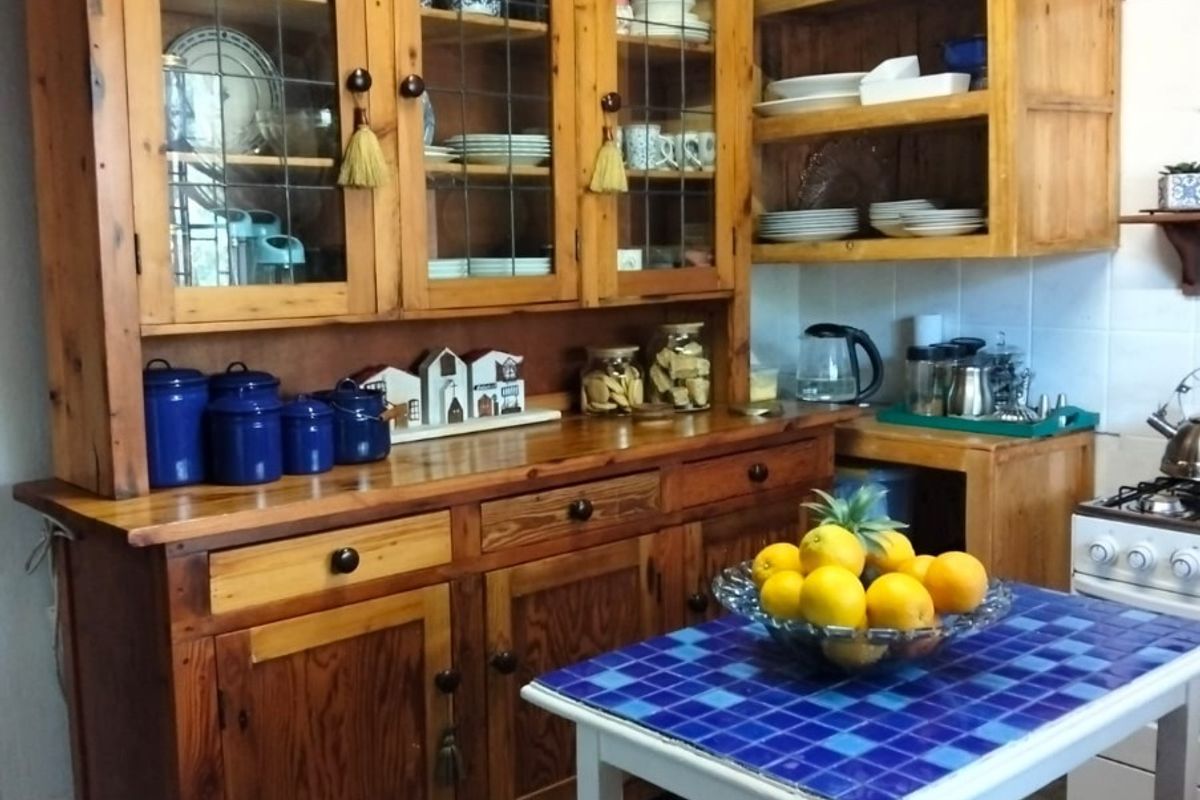 A rustic kitchen featuring traditional wooden cabinetry, exposed ceiling beams, and tiled flooring, offering a warm and characterful cooking space.