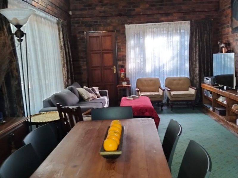 Spacious open-plan living and dining area featuring rustic exposed brick walls, high vaulted ceilings, and large windows allowing for natural light.