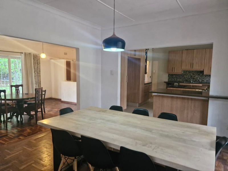 Spacious open-plan living and dining area featuring parquet flooring, a modern kitchen with built-in cabinetry, and a breakfast island.