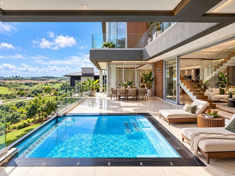Luxury outdoor pool area featuring a modern swimming pool, glass balustrades, and seamless indoor-outdoor flow to the main living space with scenic landscape views.