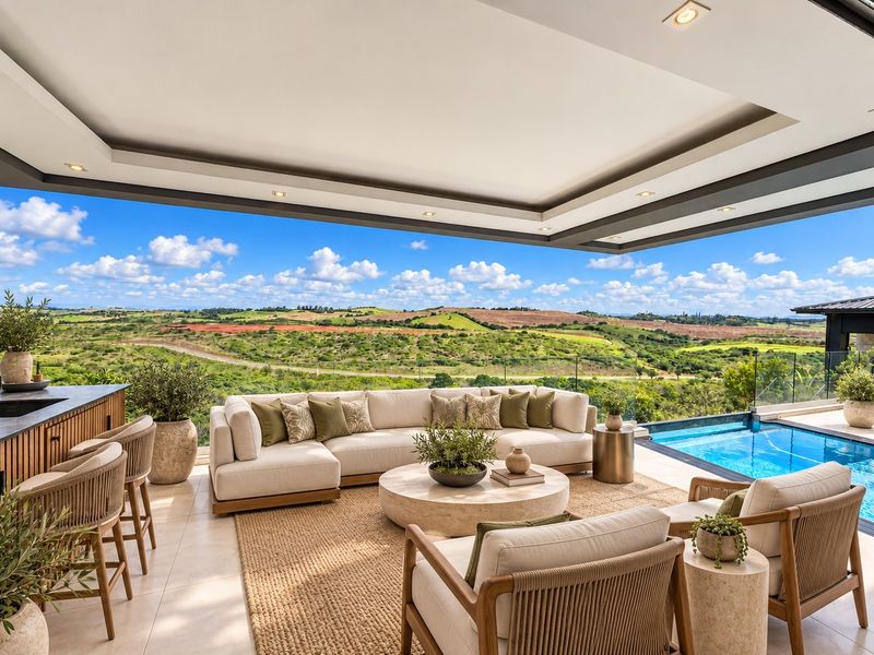Luxury covered patio featuring a built-in bar, tiled flooring, and glass balustrades overlooking a swimming pool and expansive scenic landscape views.
